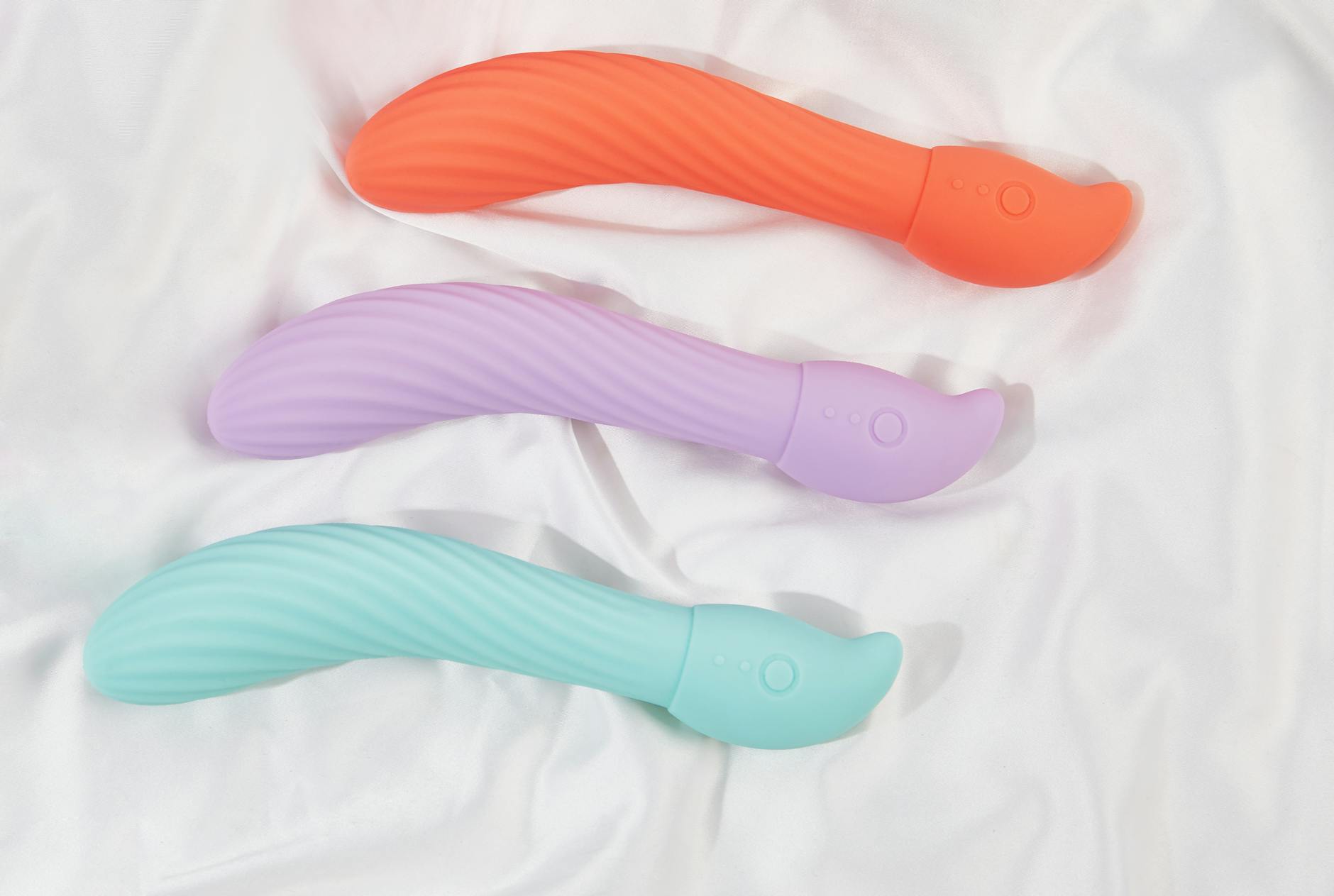 Three colorful clitoral vibrators arranged on white fabric, highlighting their smooth suction technology