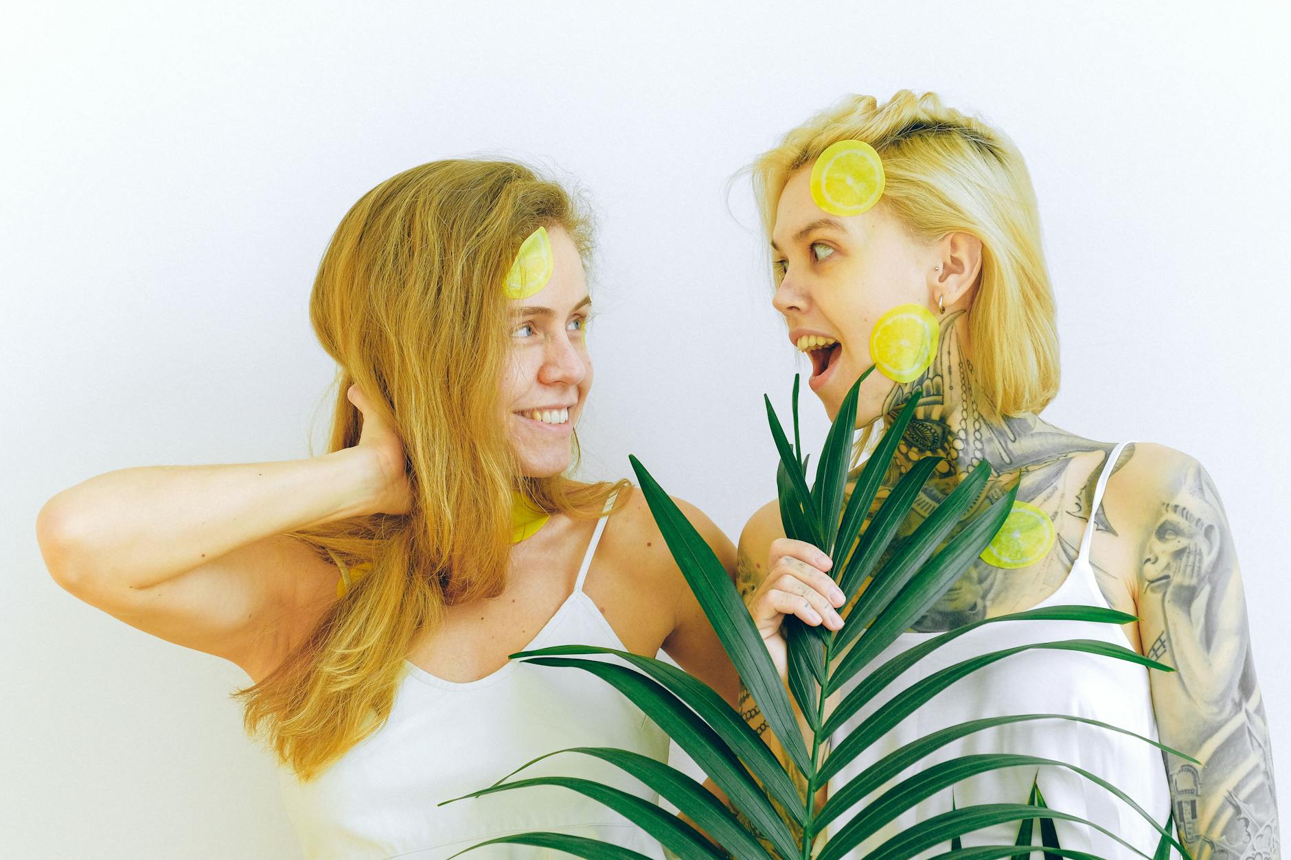 Two women smiling together with lemon slices, expressing joy and intimacy