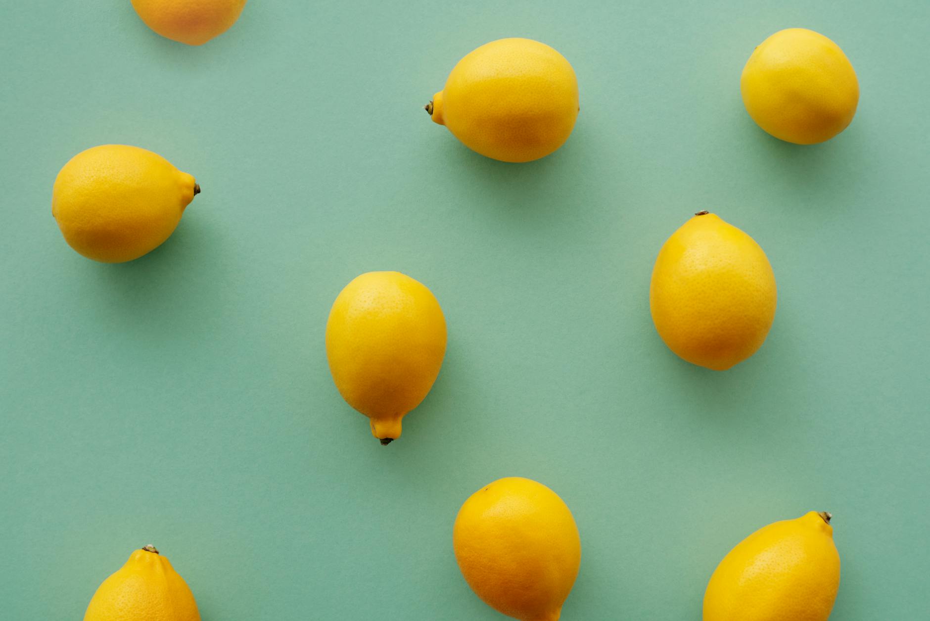 Bright yellow lemons arranged on a soft pastel green background, symbolizing fresh approaches to pleasure exploration