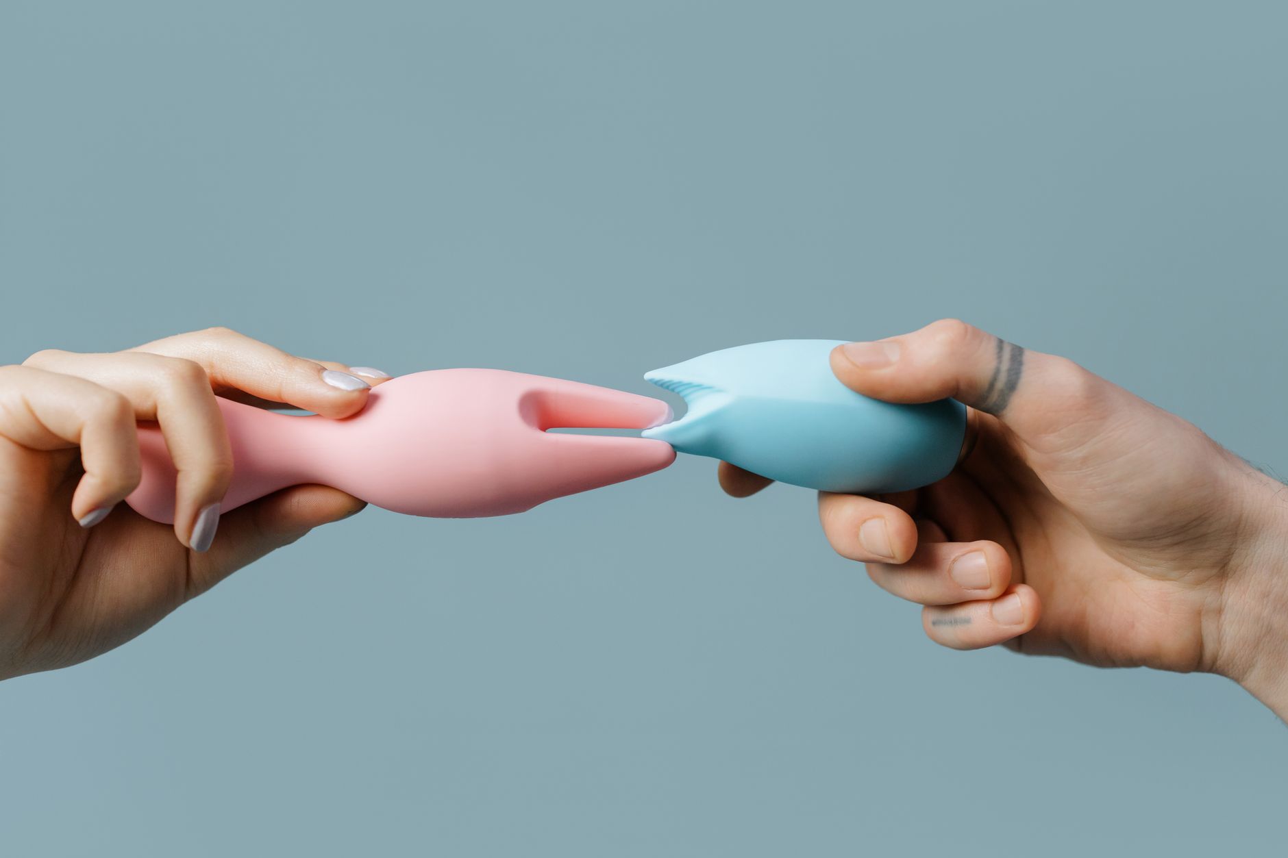 Hands holding pastel-colored silicone toys, including lemon-shaped clitoral vibrators
