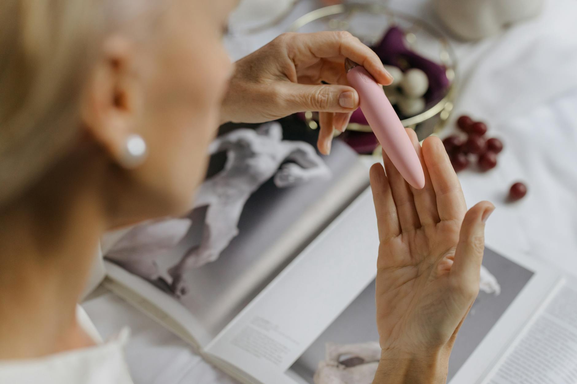 Zwei Hände halten rosa und blaue Silikonvibratorin gegen pastellfarbenem Hintergrund