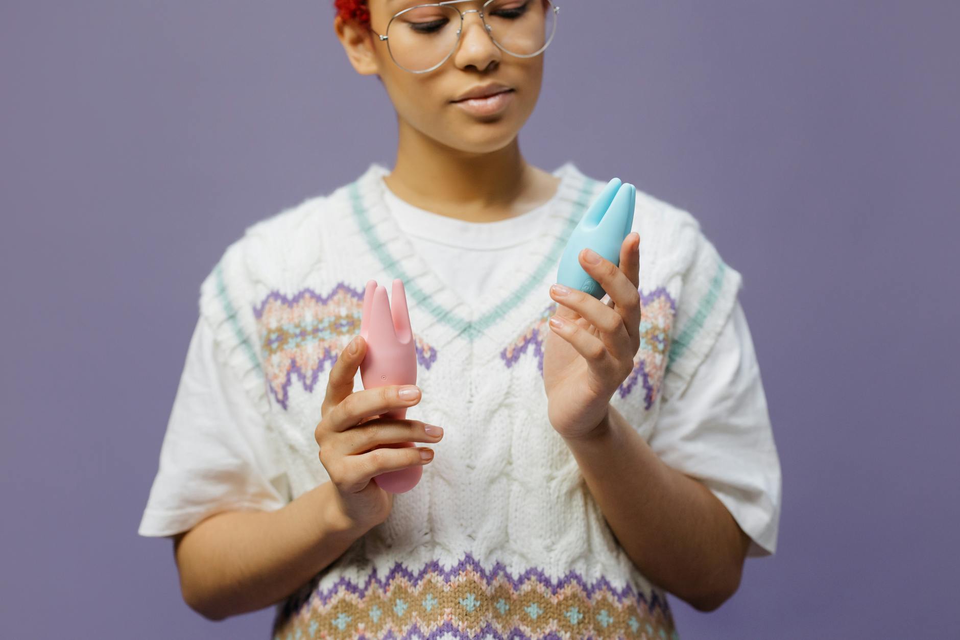 Woman holding a blue and pink silicone clitoral vibrator, exploring how sensation changes with age and hormones.