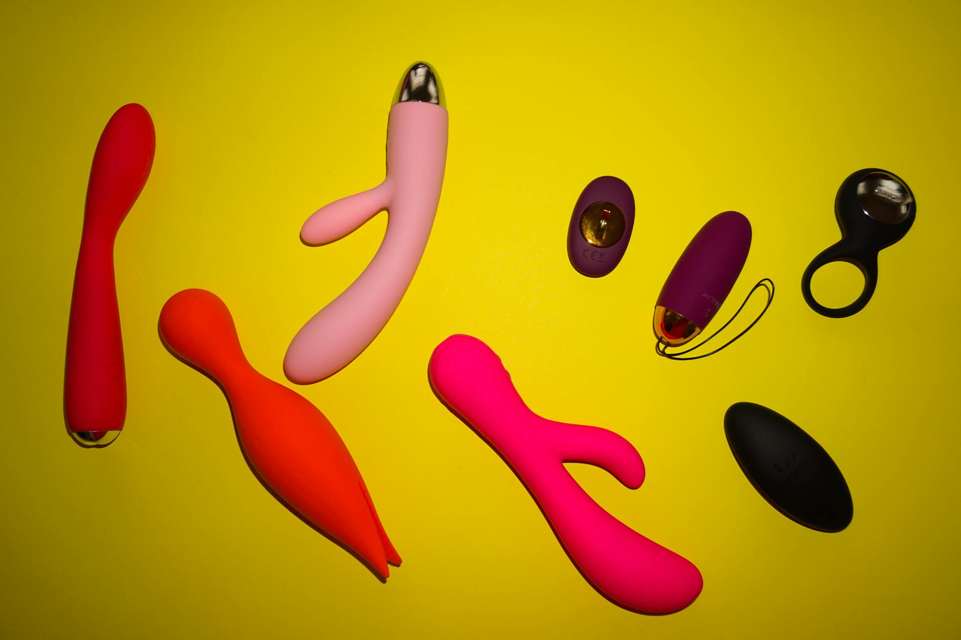 Person holding blue and pink silicone vibrators in a contemplative pose