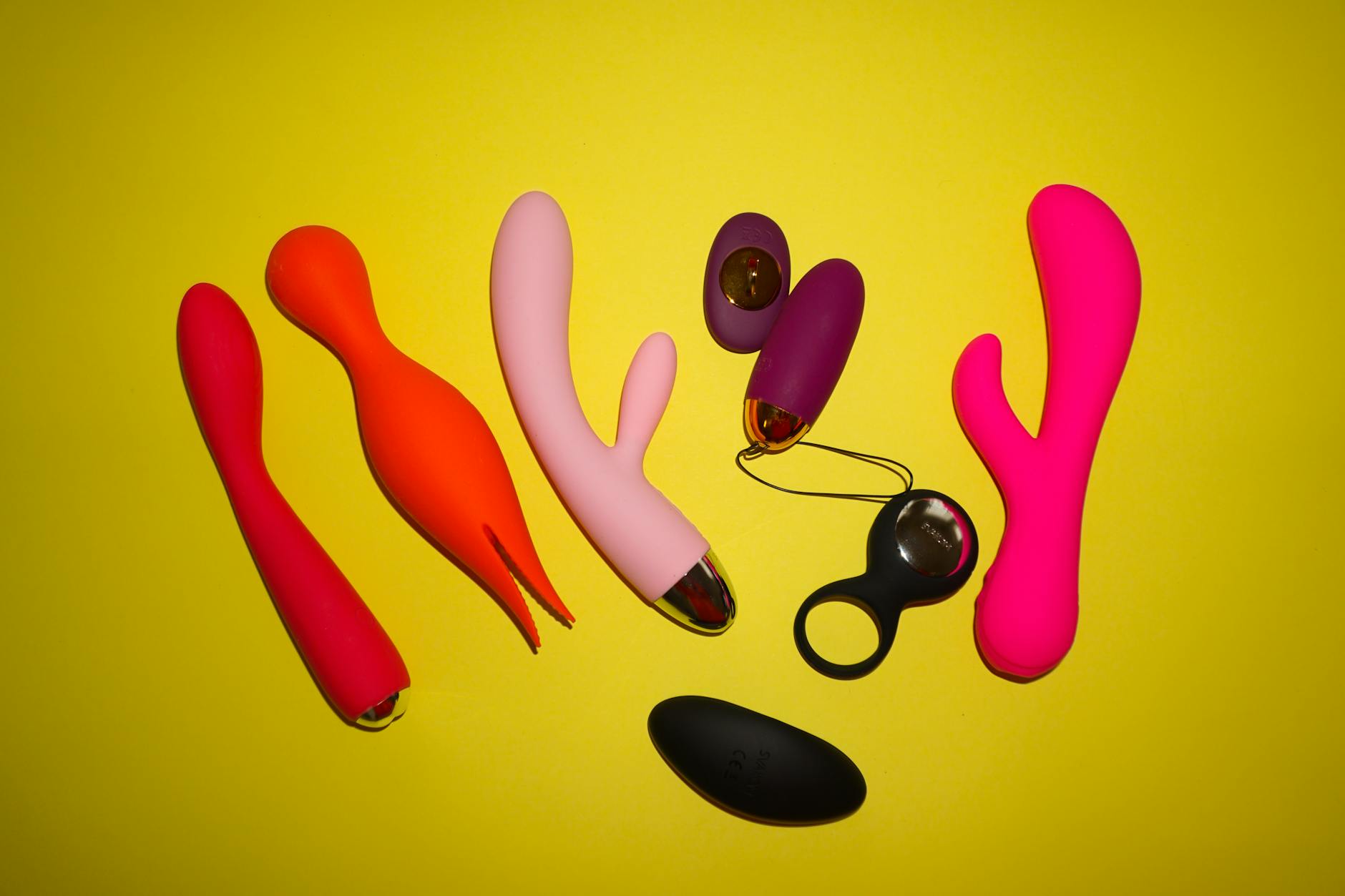 Hands holding colorful silicone sex toys in soft light