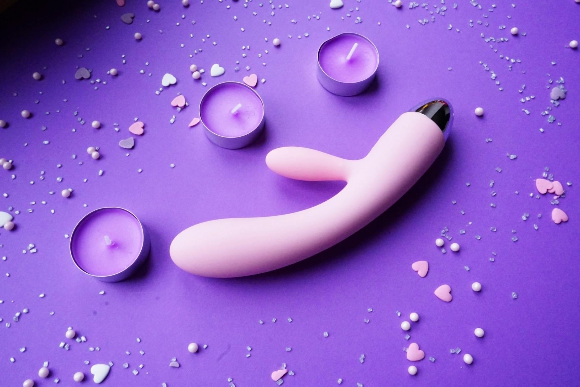 Close-up of a hand holding a vibrator against a minimalist backdrop, showing modern intimate wellness tools