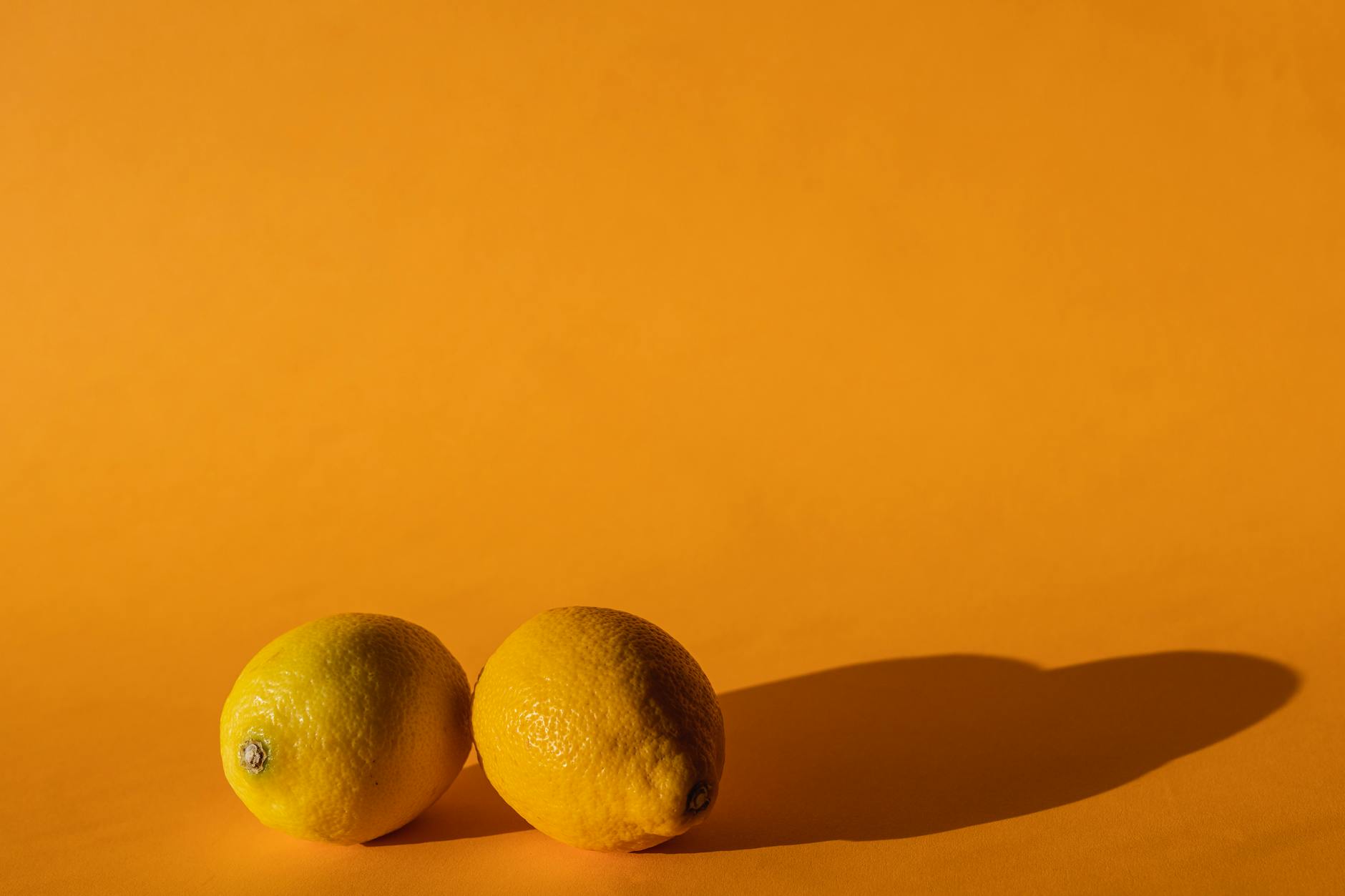 Hand holding a lemon on soft pink background, symbolizing gentle postpartum recovery